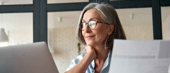 Lady on laptop with papers in hand
