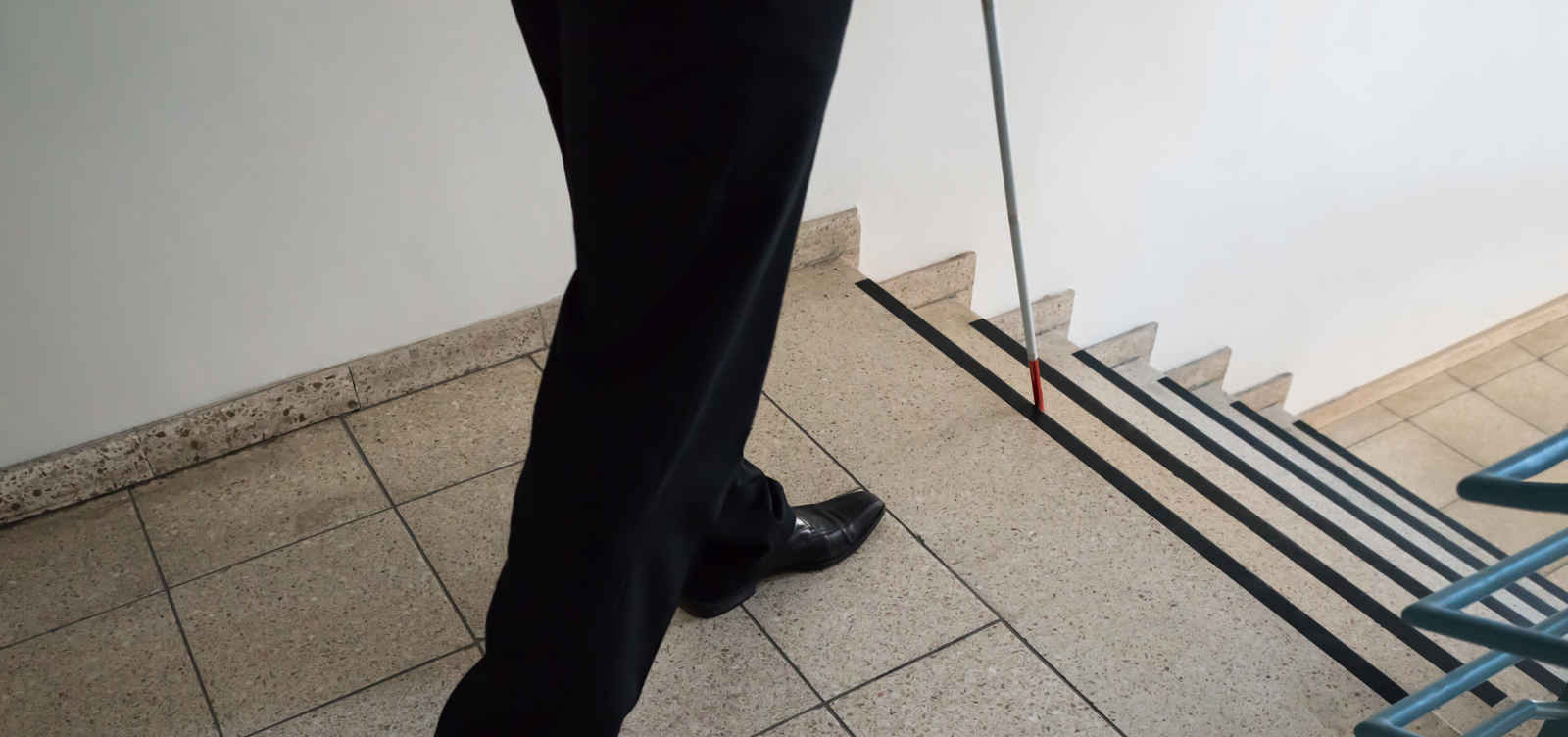 Person walking down the stairs with cane
