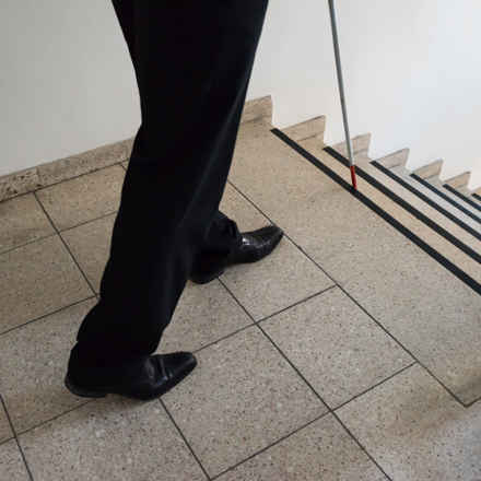 Person walking down the stairs with cane